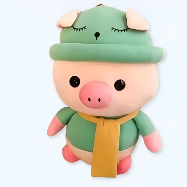 Une peluche de cochon rose avec un chapeau vert et une écharpe jaune.