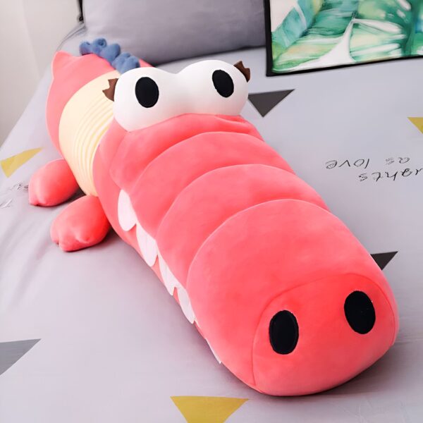 Une peluche de crocodile rose avec de grands yeux et une bouche ouverte.