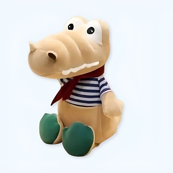 peluche-crocodile-bebe-marin-jouet-doux-enfant-1a-1 Une peluche de crocodile beige avec une écharpe rouge et un t-shirt rayé bleu et blanc, assis sur un fond blanc.
