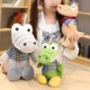 peluche-crocodile-bebe-marin-jouet-doux-enfant-3a Trois crocodiles en peluche, un gris avec un foulard rayé, un vert avec un foulard bleu et blanc et un beige avec un foulard rouge et bleu.