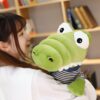 peluche-crocodile-bebe-marin-jouet-doux-enfant-4a Une jeune femme souriante tenant une peluche crocodile verte avec un t-shirt à rayures.