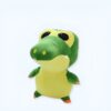 Une peluche de crocodile vert avec de grands yeux noirs et un sourire.