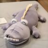 Gros coussin en forme de crocodile gris avec des yeux et des dents brodés. Parfait pour décorer une chambre d'enfant.
