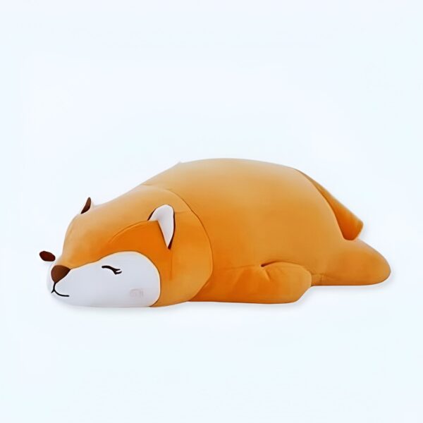 Un oreiller en forme de renard orange dormant sur le ventre.