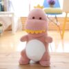 peluche-dinosaure-amusant-jouet-doux-pour-enfant-1a-4 Une peluche de dinosaure rose avec une couronne jaune debout sur un sol en bois.