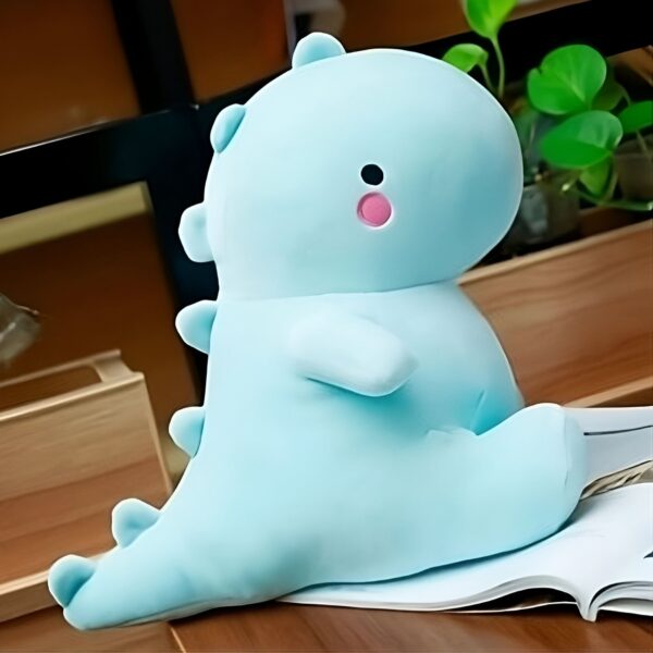 Peluche de dinosaure bleu sur un fond en bois.