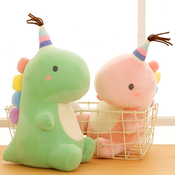Deux peluches de dinosaures, l'un vert et l'autre rose, portant des chapeaux d'anniversaire, sont assis dans un panier en métal.