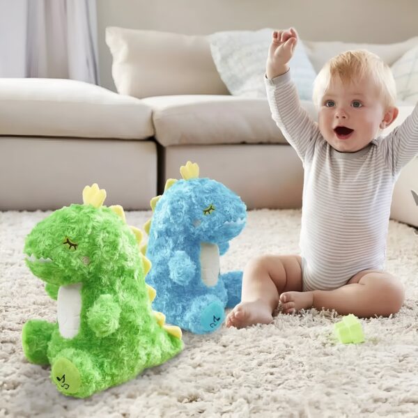 Un bébé souriant assis sur un tapis blanc, à côté de deux peluches de dinosaures, l'une verte et l'autre bleue.