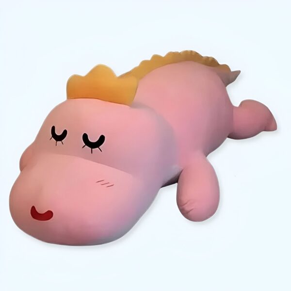 Peluche rose avec des yeux noirs et une crinière jaune, allongée sur le ventre.