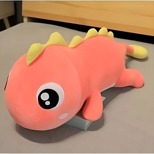 Une peluche rose en forme de dinosaure avec de gros yeux noirs et une crête jaune.