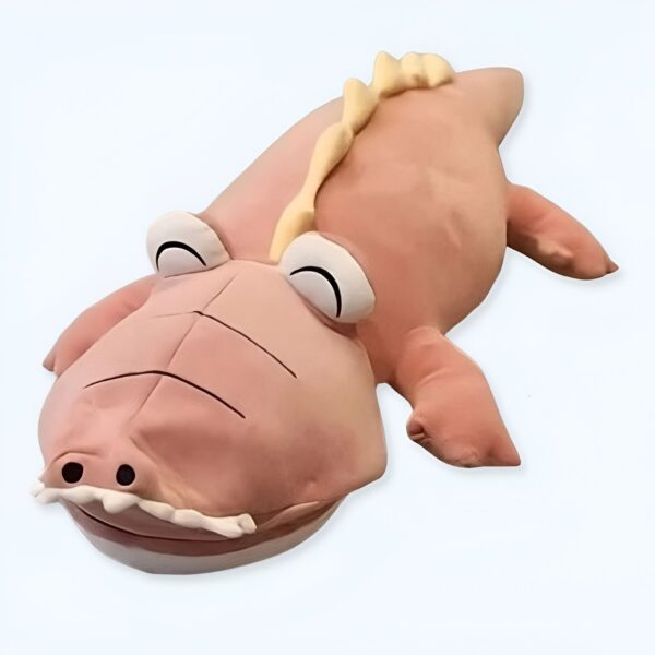Gros plan d'un grand crocodile rose en peluche avec des yeux et un sourire rigolos.