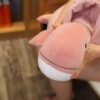peluche-dinosaure-rose-magique-3a-2 Gros plan sur une baleine en peluche rose et blanche tenant dans les mains d'une personne.