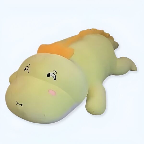 Une peluche verte en forme de dinosaure avec des yeux noirs et des joues roses allongée sur le dos.