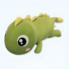 Peluche de dinosaure vert avec de grands yeux noirs et une petite bouche rose.