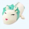 Une peluche blanche avec une crinière turquoise et un sourire rose.