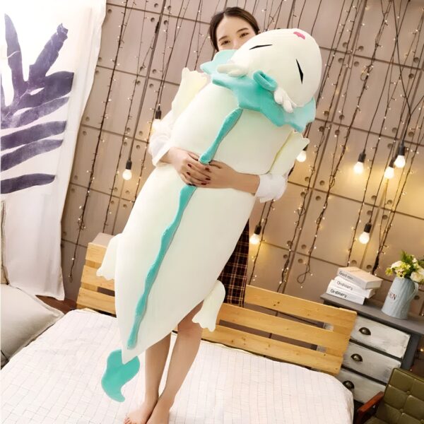 Une jeune femme souriante tenant une grande peluche blanche en forme de dragon avec des ailes turquoise.