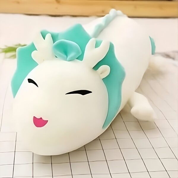 Peluche de dragon blanc avec des détails bleus et des yeux noirs souriants.