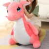 Une femme assise sur un canapé avec une grande peluche rose en forme de dragon.