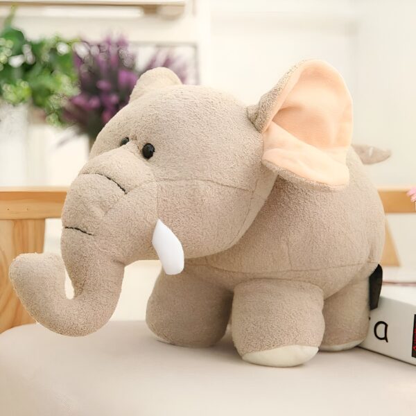 Une peluche d'éléphant beige avec de grandes oreilles et de petites défenses en peluche.
