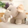 Une peluche d'éléphant beige avec de grandes oreilles et de petites défenses en peluche.