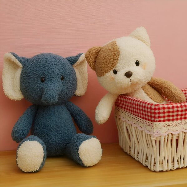 Un éléphant en peluche bleu et un chiot en peluche blanc et brun assis sur un fond rose. Le chiot est assis dans un panier en osier avec une doublure rouge et blanche à carreaux.