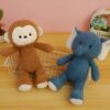 Deux peluches, un singe brun et un éléphant bleu, assis sur un fond en bois.
