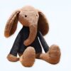 Un éléphant en peluche brun portant un chandail noir assis sur un fond blanc.