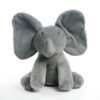 Peluche éléphant gris assis sur un fond blanc, les oreilles relevées.