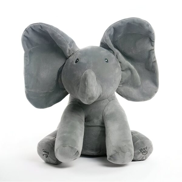 Un éléphant en peluche gris assis sur un fond blanc. L'éléphant a de grandes oreilles et un petit tronc.