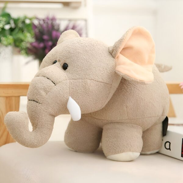 Une peluche d'éléphant en peluche beige avec de grandes oreilles et des défenses blanches.