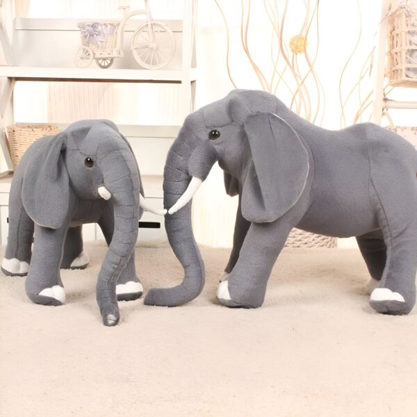 Deux éléphants en peluche gris, l'un plus grand que l'autre, sur un tapis blanc.