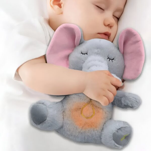 Un bébé dort paisiblement en tenant un éléphant en peluche gris avec des oreilles roses. L'éléphant a des yeux fermés et un ventre orange.