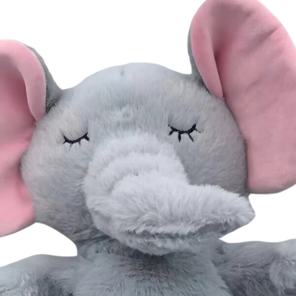 Un éléphant en peluche gris avec de grandes oreilles roses, les yeux fermés.