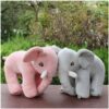 Deux éléphants en peluche, un rose et un gris, se tiennent côte à côte sur un fond vert.