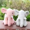 Deux éléphants en peluche, un rose et un gris, posés sur une table en bois.