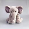 Une peluche d'éléphant gris assis avec de grandes oreilles roses.