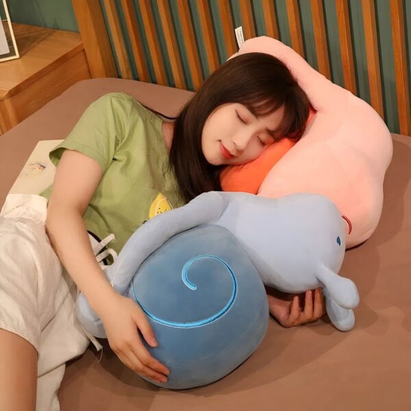 Une jeune femme dort sur un lit avec deux oreillers en forme d'escargots, un bleu et un rose.