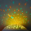 Une lampe de projection pour enfants projetant des étoiles et une lune sur le plafond.
