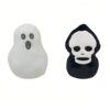 Deux coussins en peluche d'Halloween, l'un en forme de fantôme blanc et l'autre en forme de crâne noir.