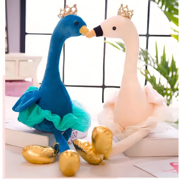 Deux peluches en forme de cygne, l'une bleue avec une jupe turquoise et l'autre rose avec une jupe blanche, portant des couronnes dorées et entourées de ballons dorés.