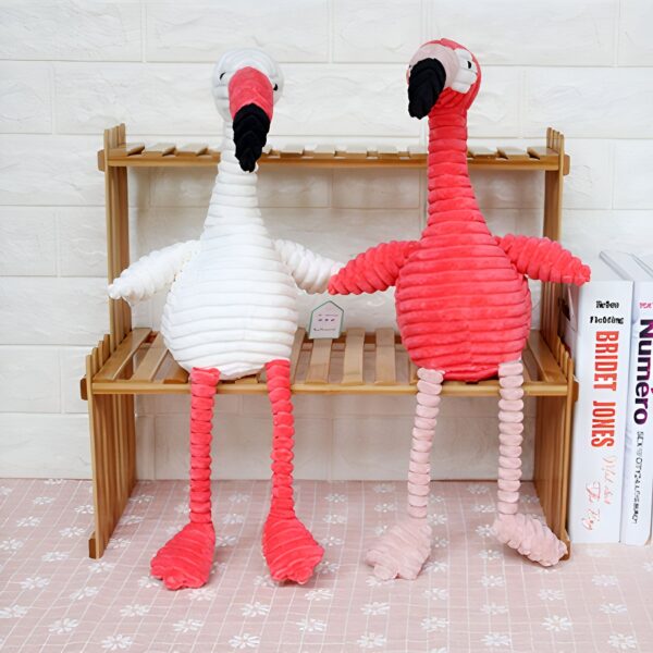 peluche-flamant-rose-coton-cotele-jouet-doux-bebe-3a-2 Deux flamants roses en peluche, un blanc et un rose, sont assis sur une étagère en bois.