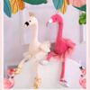 Deux peluches de flamants roses, l'une en rose et l'autre en blanc, portant des tutus et des chaussures dorées.