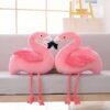 peluche-flamant-rose-jouet-en-peluche-doux-pour-enfant-decoration-chambre-4a Deux peluches flamants roses sont assises sur un canapé et se regardent. Les flamants roses sont en peluche rose et ont des pattes et des becs longs et fins.