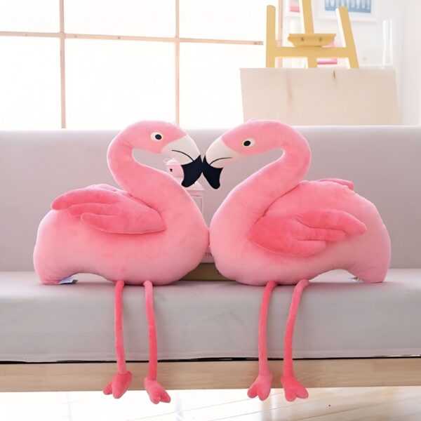 peluche-flamant-rose-jouet-en-peluche-doux-pour-enfant-decoration-chambre-4a Deux peluches flamants roses sont assises sur un canapé et se regardent. Les flamants roses sont en peluche rose et ont des pattes et des becs longs et fins.