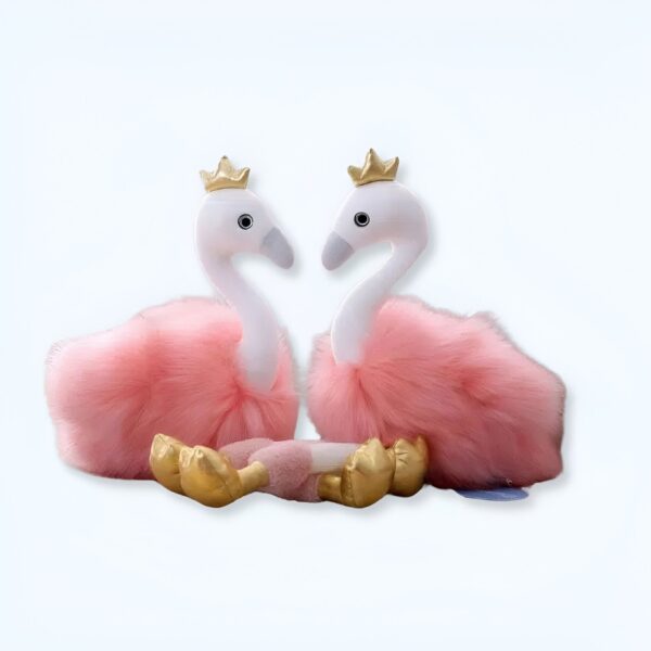 Deux flamants roses en peluche avec des couronnes dorées, assis l'un en face de l'autre.