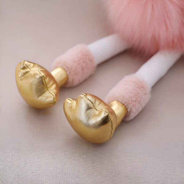 peluche-flamant-rose-princesse-avec-couronne-et-chaussures-dorees-cadeau-enfant-6a Les pieds dorés d'une poupée en peluche rose et blanche.