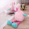 peluche-flamant-rose-rigolote-4a Deux peluches de flamants roses assis sur un sol en bois. Les flamants ont des points roses sur leurs pattes et leurs corps sont en fourrure rose.