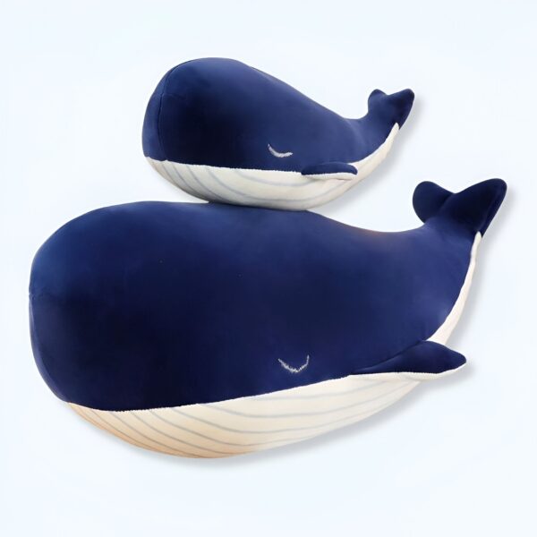 Deux baleines en peluche bleue, l'une sur l'autre, avec des yeux brodés et des rayures blanches.