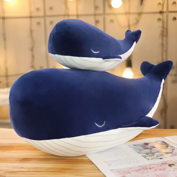 Deux baleines en peluche bleu foncé avec des yeux brodés et des rayures blanches sur le ventre.