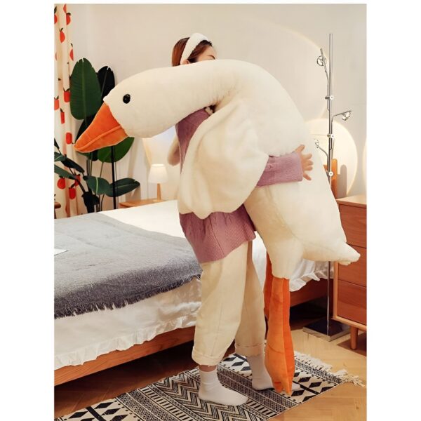 Une femme tient un grand oreiller en forme d'oie blanche. L'oreiller est moelleux et confortable, parfait pour se blottir.